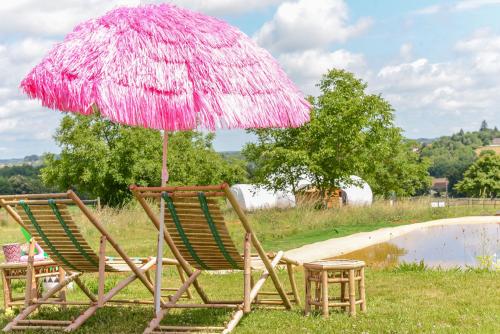 dos sillas bajo una sombrilla rosa junto a una piscina en LA NOALHA INSOLIT' en Lanouaille