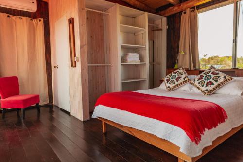 a bedroom with a large bed and a red chair at BDL Beach Design Loft One in José Ignacio