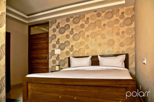 德拉敦的住宿－Paradise Inn，一间卧室配有一张大床和木制床头板