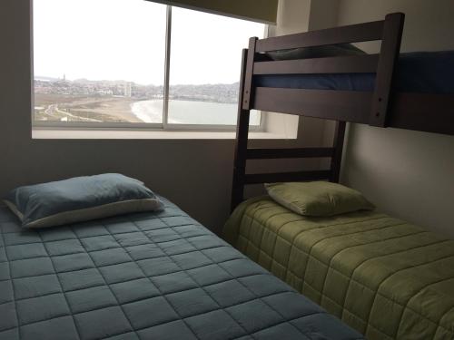 a bedroom with two bunk beds and a window at Costa Mansa II, Avenida Costanera 3100 , Departamento 2201 in Coquimbo