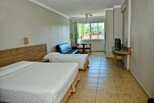 a hotel room with two beds and a chair at De Rose Praia Hotel in Torres