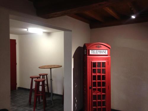- une cabine de téléphone rouge dans une pièce avec une table dans l'établissement La pause verte, à Acqueville