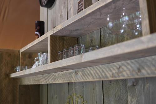 a wooden shelf with glasses and wine glasses on it at Au Coeur De Lolhm in Le Buisson de Cadouin