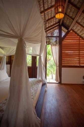 a bedroom with a bed with a canopy at La Ferme De Georges in Atins