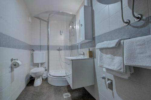 a white bathroom with a toilet and a sink at Tihe Noci Motel in Pale