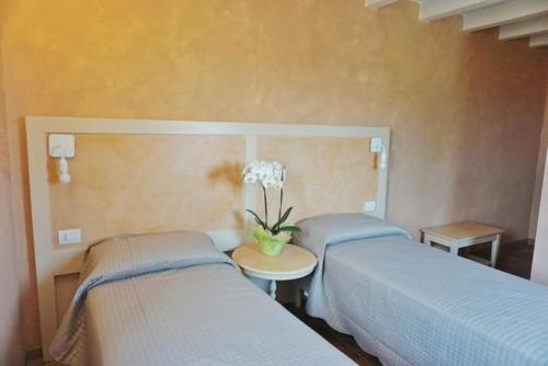 two beds in a room with a table with a vase of flowers at agriturismo campogrande in Carpaneto Piacentino