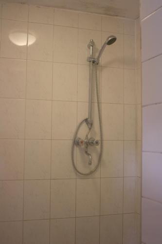 a shower in a white tiled bathroom at Hostel The Veteran in Amsterdam