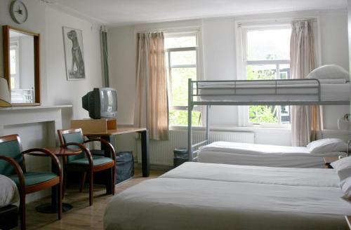 Un dormitorio con dos camas y un escritorio y un televisor. en Hostel The Veteran, en Ámsterdam
