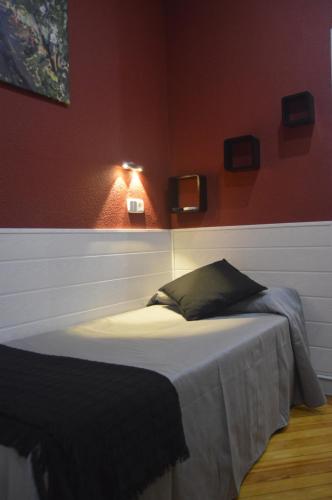 a bed in a room with a red wall at Hostal Aresol in Madrid