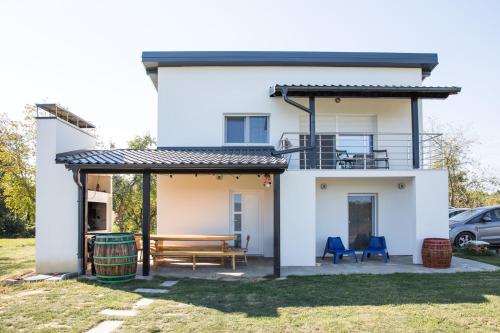 a white house with a bench and a deck at Kuće za odmor -Japin breg in Ðurđevac