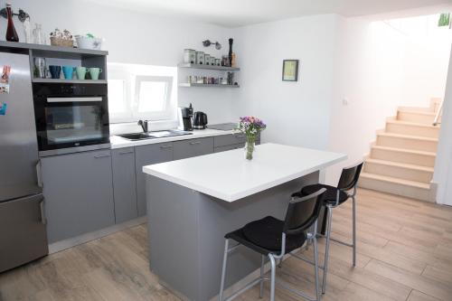 a kitchen with a white island with two chairs at Kuće za odmor -Japin breg in Ðurđevac