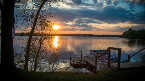 a dock on a lake with the sun setting at Curriers Lakeview Lodge in Rice Lake