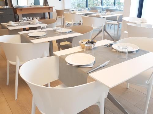 a restaurant with white tables and white chairs at Hotel Enight in Gradignan