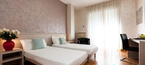 a hotel room with two beds and a couch at Hotel Lis in Asti