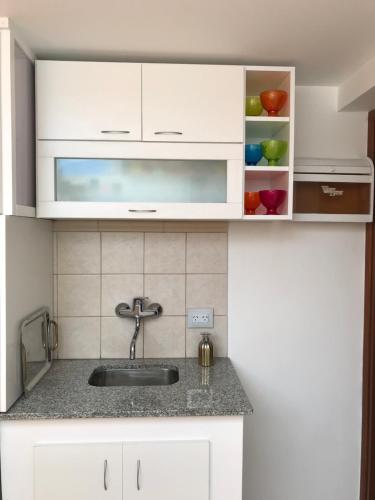 a kitchen with white cabinets and a sink at Casamia Altos in Bahía Blanca