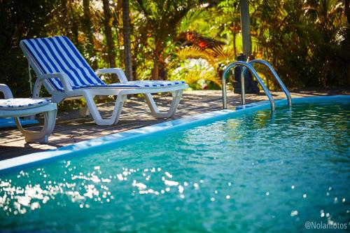 two chairs sitting next to a swimming pool at Pousada Watu Kerere in Praia do Rosa