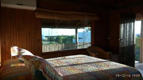 um quarto com uma cama e uma grande janela em Hotel El Refugio nudista naturista opcional em Punta del Este