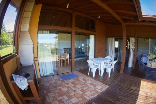 a screened in porch of a house with a table and chairs at Pousada Watu Kerere in Praia do Rosa