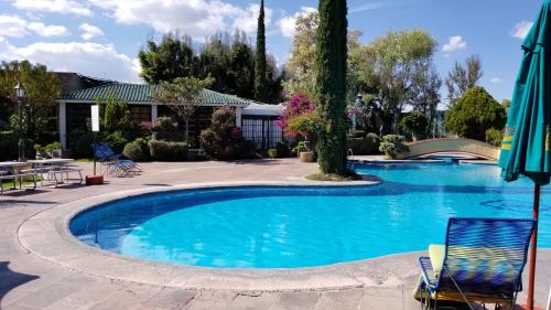 a swimming pool with two chairs and an umbrella at Gran Hotel Hacienda De La Noria in Aguascalientes