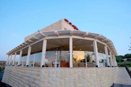 a pavilion with tables and chairs on a stone wall at Tantur Hills Hotel - Jerusalem in Jerusalem