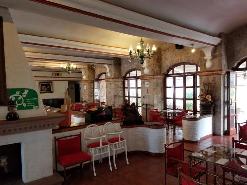 a restaurant with red chairs and tables and a fireplace at Gran Hotel Hacienda De La Noria in Aguascalientes