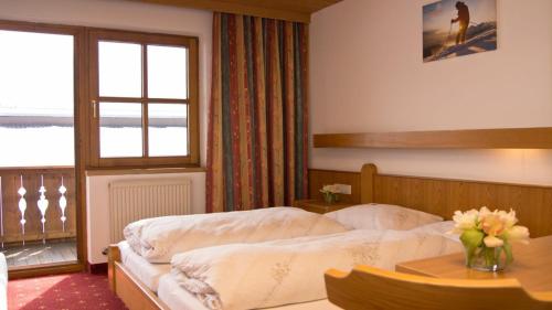 a bedroom with a bed and a table with flowers on it at Pension Traube in Uderns
