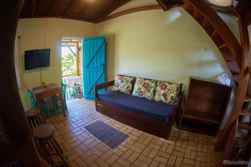 a living room with a blue couch and a tv at Pousada Watu Kerere in Praia do Rosa