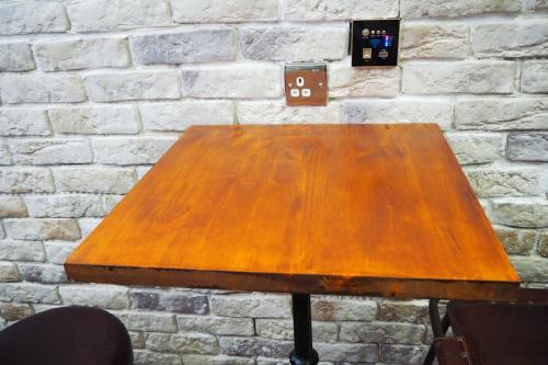 a wooden table in front of a brick wall at Tiny apartment on the roof touching Gibraltar in La Línea de la Concepción