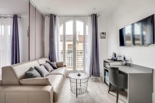 a white living room with a couch and a table at Paris Hotel in Clichy