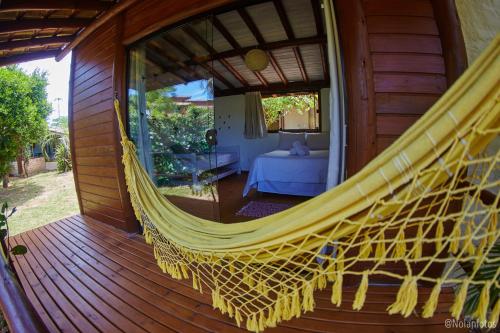 a hammock on a porch of a house at Pousada Watu Kerere in Praia do Rosa