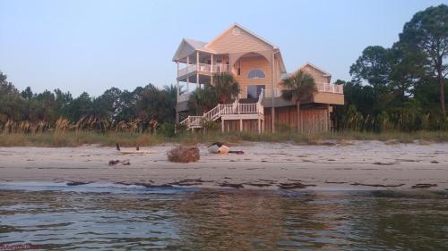 a house sitting on the beach next to the water at Paradise by the Sea in Carrabelle