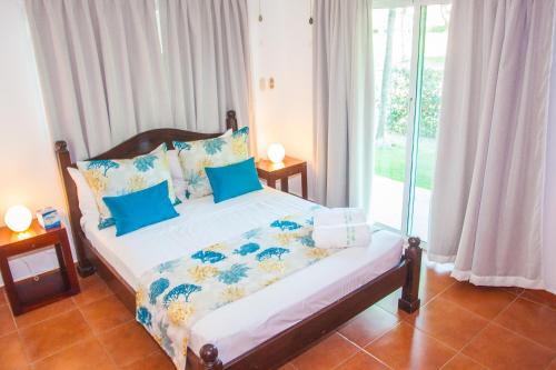 a bedroom with a bed with blue pillows and a window at Cocotal Bavaro Apartments in Punta Cana
