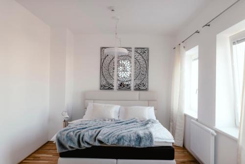 - une chambre blanche avec un lit et un lustre dans l'établissement Luxury Apartments Zelny Trh, à Brno