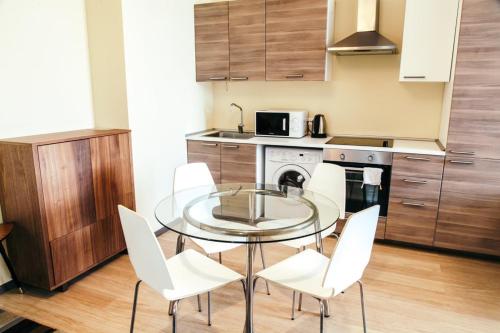 ソチにあるPremier Apartmentのキッチン(ガラステーブル、白い椅子付)