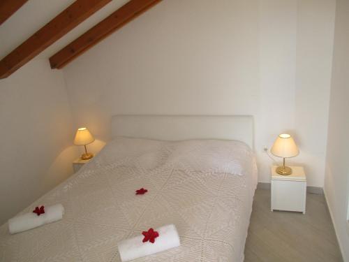 a bedroom with a white bed with red flowers on it at Apartments Carol in Sreser