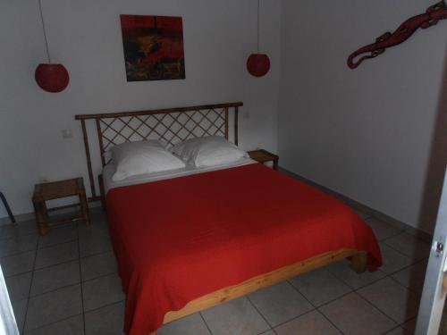 a bedroom with a bed with a red blanket and white pillows at Les Manguiers in Deshaies