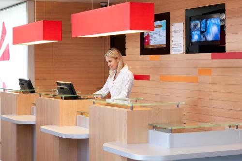 a woman sitting at a counter using a laptop at Ibis Barcelona Santa Coloma in Santa Coloma