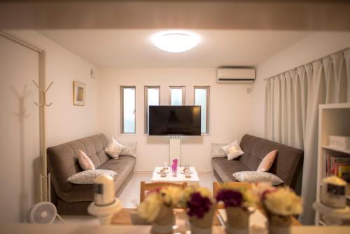 a living room with two couches and a tv at COCO Shinjuku HOTEL in Tokyo