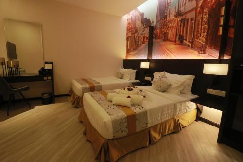 a hotel room with two beds and a painting on the wall at Amamas Boutique Hotel Kuching in Kuching