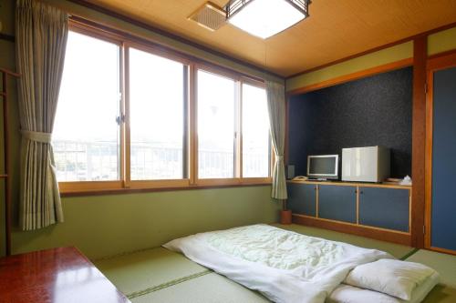 um quarto com uma cama num quarto com janelas em Hotel Jodai em Unnan