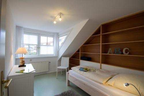 a bedroom with a bed and a desk and a staircase at Ferienhaus *Traumblick* in Wittdün