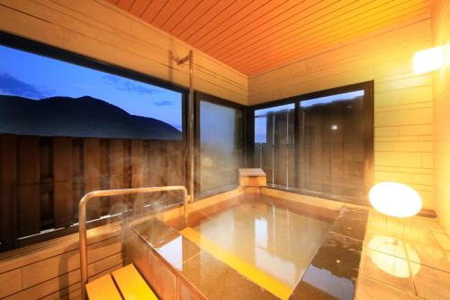 a jacuzzi in a room with large windows at Tensui Saryo in Hakone
