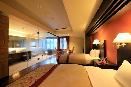 a hotel room with two beds and a bathroom at Tensui Saryo in Hakone