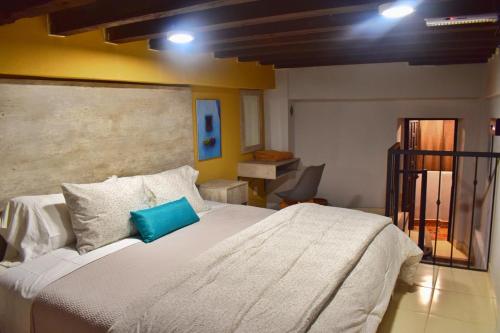 a bedroom with a large white bed with a blue pillow at Hotel Corazón Mexicano in Guanajuato
