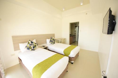 two beds in a hotel room with a tv at Eon Centennial Soho Hotel in Cebu City