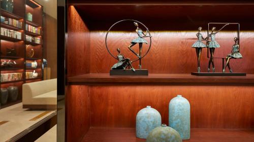 a shelf with two figurines and two vases on it at SSAW Boutique Hotel Ningbo CBD - Family Friendly & Business Travel in Ningbo