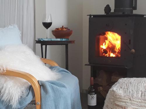 a bedroom with a fireplace with a bed and a glass of wine at Mapua Studio Quality Accommodation in Mapua