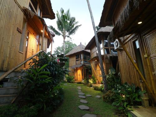 a path between two buildings with a palm tree in the background at Biyukukung Suite & Spa in Ubud