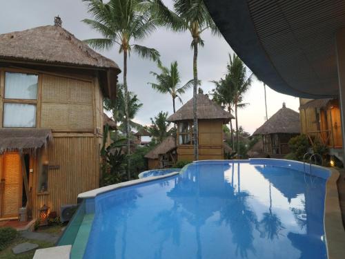 a swimming pool in a resort with palm trees at Biyukukung Suite & Spa in Ubud