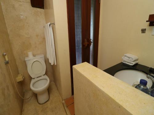 a bathroom with a toilet and a sink and a tub at Biyukukung Suite & Spa in Ubud